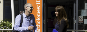 Two adults engage in conversations outside of a council building