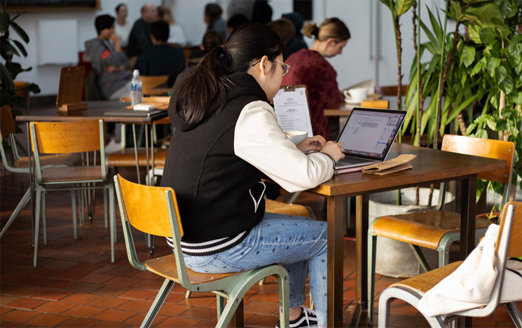 Student studying at computer at a cafe on campus at the University of Sussex