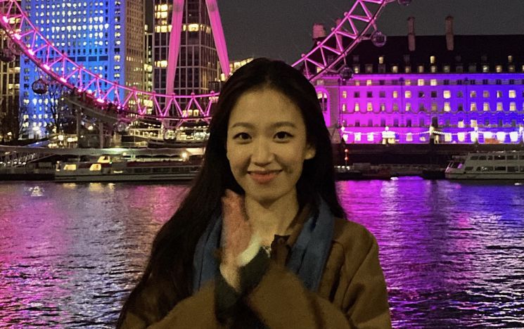 Student smiling outside at night in front of London Eye lit up