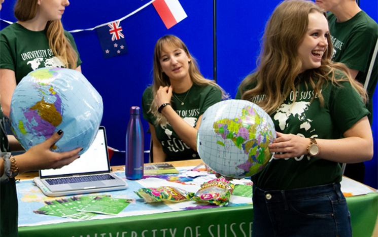 Four members of Geography Society at a fayre table smiling