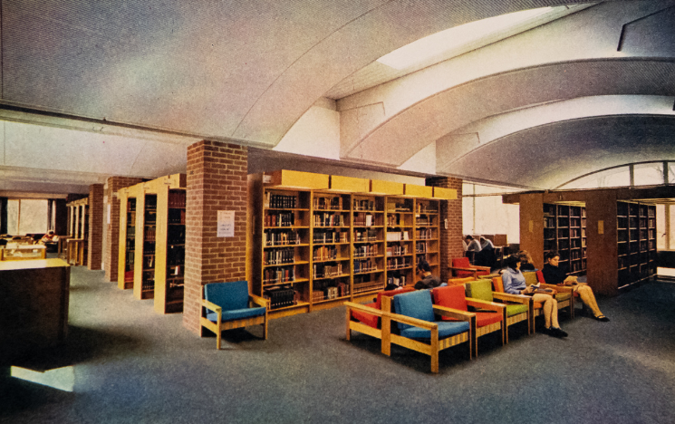 An old photo of the inside of the Library including students sat in multicoloured chairs