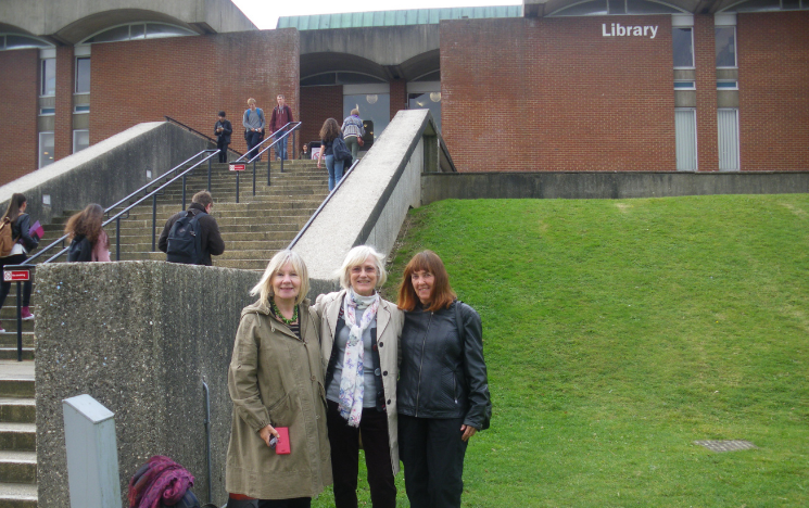 A photo of alumnae Vivienne, Teresa and Stephanie smiling at the foot of the Library stairs when they revisited it in 2016