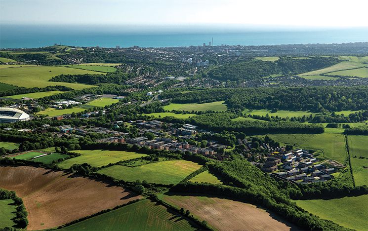 Aerial shot of campus in the green of the south downs, with the sea in the background
