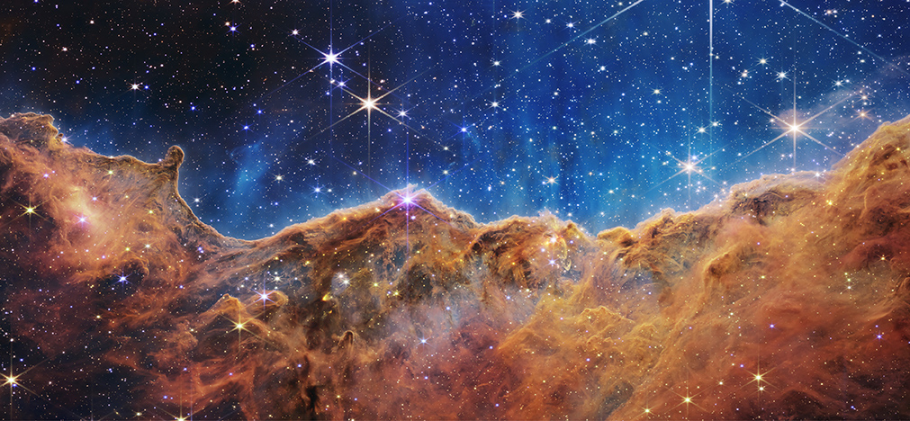 JWST NIRcam image of Cosmic Cliffs in the Carina Nebula resembling mountains against a starlit sky