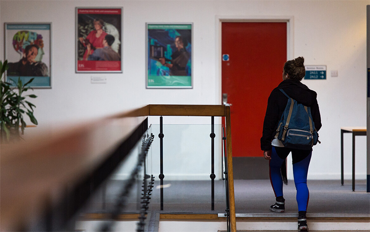 Student walking up the stairs in the Pevensey building, where the Bridge cafe is located