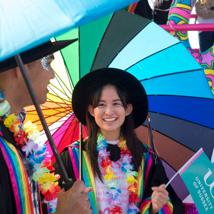 Students at Pride with a multi-coloured umbrella.