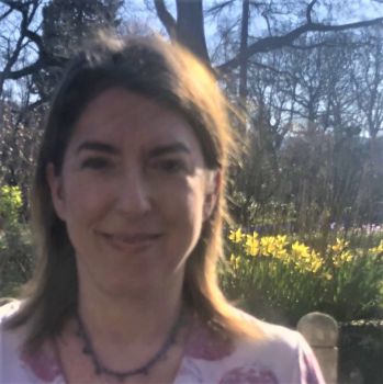 University of Sussex researcher Cassandra Wiener smiles at the camera with spring daffodils behind her