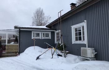 A blue one storey home fitted with a heat pump surrounded by heavy snow