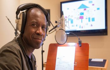 Clive Myrie wearing headphones about to speak into a microphone