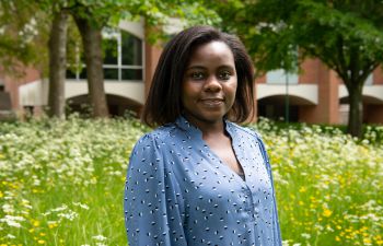 Tamanda Maggie Gomani, Mandela Scholar, in front of grass and a red brick Sussex campus building