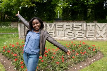 Tamanda Maggie Gomani, Mandela Scholar, in front of the carved concrete University of Sussex sign on campus