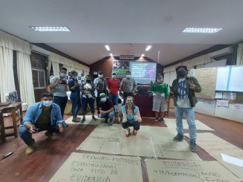 Students wearing masks and giving the thumbs up surrounded by flipchart paper on the floor