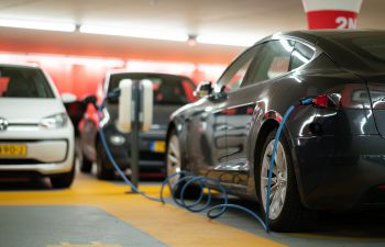 Black, white and grey electric cars are parked and being charged in a multi-storey car park