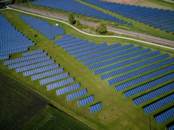 Rows and rows of blue solar panels on a green hill