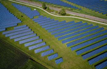 Rows and rows of blue solar panels on a green hill