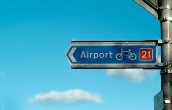 A blue sign pointing the route of a cycle lane to an airport