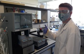 Charlie in the Chemistry lab with a face covering, giving a thumbs up