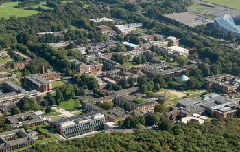 An aerial view of the University of Sussex campus showing the buildings among the green of trees
