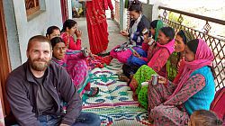 Steve Orchard smiling and sitting with women in Dehradun city