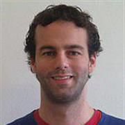 A close-up headshot of Folkert Kuipers with dark hair and a brightly coloured round neck jumper