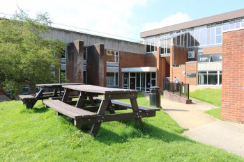 The north door accessibility entrance of the Library. An empty picnic table is seen on the grass outside the north door entrance.