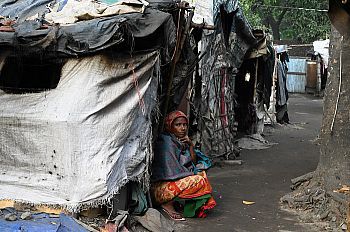 A woman of colour sitting on the floor with her back against tents made with scraps