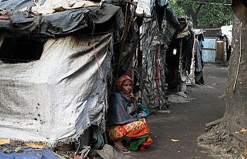 A woman of colour sitting on the floor with her back against tents made with scraps