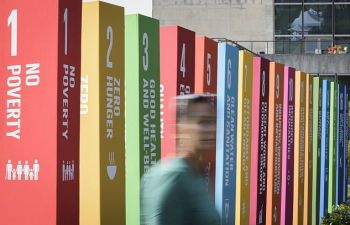 Woman passing by in front of banners representing each of the sustainable development goals