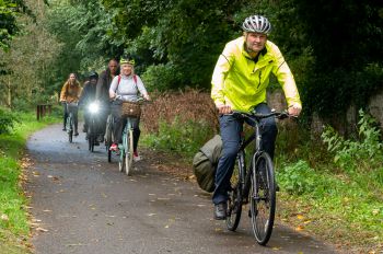 Adam Tickell cycles ahead of four other cyclists, leading them on the cycle path onto campus