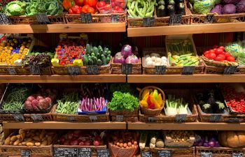 A wide variety of fruit and vegetables stacked on supermarket shelves