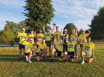 Group photo of TeamSussex runners waving at the camera in Preston Park before the Brighton Marathon events