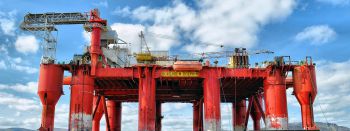 A large red oil drilling platform looms out of the sea