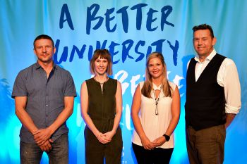 From left to right: Mika Peck, Lucy Hughes,  Melissa Lazenby and Pete Newell stand in front of a light blue backdrop which reads 'A Better University for a Better World'