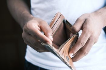 A man opens up his brown leather wallet to reveal that it is empty