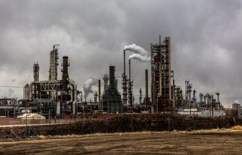 A heavy industrial site with tall towers spewing pollution into the atmosphere