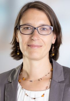 Head and shoulders photo of Prof Karoline Rogge who is wearing a grey jacket, white top and glasses