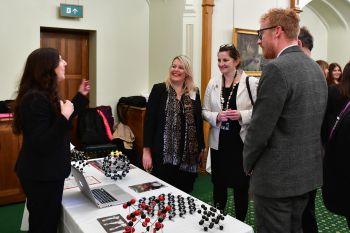 Two men and three women standing around a table having a discussion