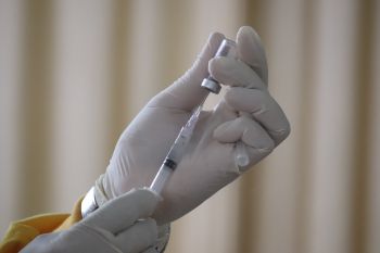A pair of hands wearing surgical gloves handle a medical needle