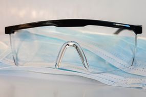 A pair of protective goggles pictured on top of single use face masks