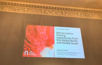 high ceilinged wall with powerpoint slide projected onto it. Slide reads The British Academy, 4-6 October 2021, Menstruation: sharing experiences from the global north and global south', conference conveners: professor kay standing, liverpool john moores