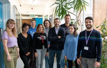 Nine members of Professor Georgios Giamas' lab stand facing and smiling at the camera.