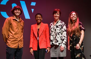 Four people stand on a drama stage