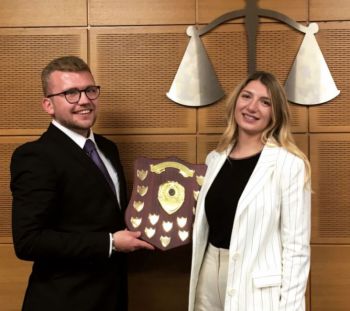 George Grammer-Taylor and Samantha Smith standing together, smiling holding shield in moot room