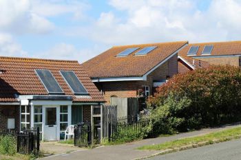 Photo of single-storey houses with discoloured solar panels on the roof