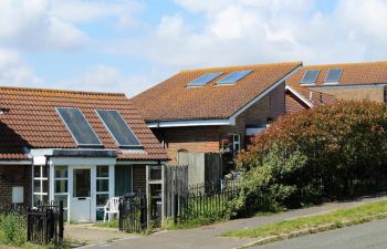 Photo of single-storey houses with discoloured solar panels on the roof