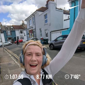 Sam holds an arm in the air celebrating her best run yet, the details of which show up at the base of the image (8.77km in 1 hour and 8 minutes)