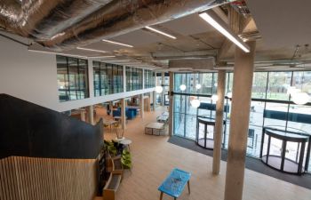 View of the Student Centre entrance hall from the first floor. The floor to ceiling glass walls, concrete pillars and wooden floors gives the spacious atrium a fresh and modern look