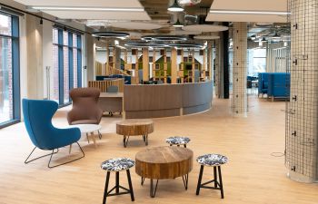 A modern space with a semi-circular reception desk, some stools and couple of armchairs around low coffee tables.