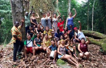 A group of people standing and sitting in a forest and raising their fists in solidarity