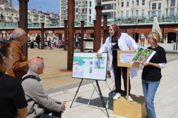 A scientist in a lab coat talking to people on Brighton seafront